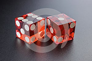 Two red dice on a black background with light.