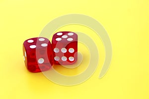 Two red dice lie on a yellow background with space for text.