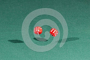 Two red dices falling on a green table