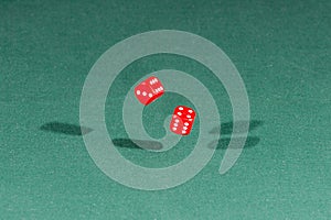 Two red dices falling on a green table