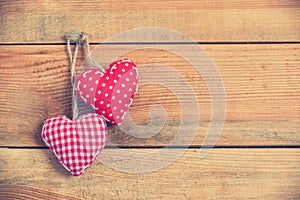 Two red fabric hearts on old wood background, vintage process