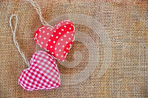 Two red fabric hearts on rustic canvas
