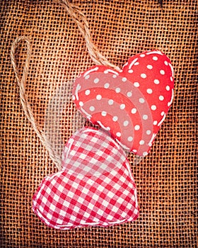 Two red fabric hearts on rustic canvas background