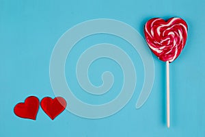 Two red fabric hearts and sweet bright lollipop heart on blue ba