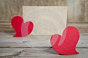 Two red fabric hearts on a wooden board