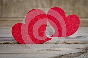 Two red fabric hearts on a wooden board