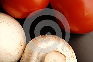 Two red fresh tomatoes. Mature. Dimmed light. On black background.