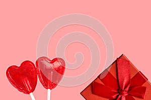 Two red fruits lollipop heart shape candies gift box with bow on pink background. Romantic Valentines love concept