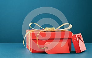 Two red gift boxes on blue. Golden bow