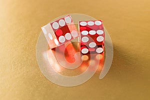 Two red glass dice on a gold background with reflection. The result is six and on the edge