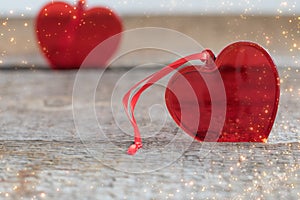 Two red glass hearts on wooden background, with textured glitter, St Valentines Day postcard