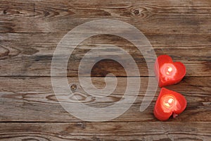 Two red heart shape candles on wooden table, top view