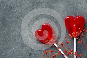 Two Red Heart Shape Candy Lollipops on Sticks Flowers on Dark Stone Background. Valentine Romantic Love Greeting Card