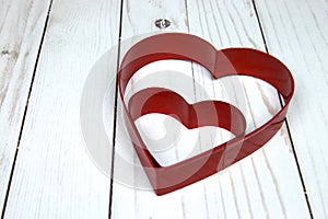 Two Red Heart Shaped cookie Cutter on wooden White back