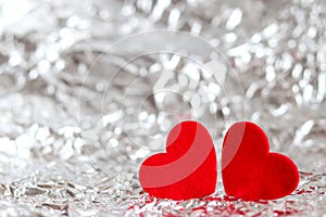 Two red hearts against shiny silver background with copy space. Valentine's Day and love concept. Selective focus