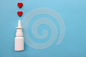 Two red hearts and a bottle of nasal spray on a blue background. Healthcare. Vasoconstrictors