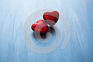 Two red hearts on dark blue or silver on wooden or metal background. Valentine`s Day