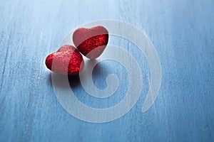 Two red hearts on dark blue or silver on wooden or metal background. Valentine's Day