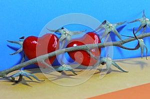 Two red hearts on an empty branch from cherry tomatoes on a blue orange yellow background