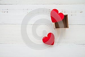 Two red hearts go out paper box on white wooden background - val