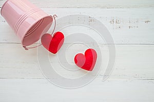 Two red hearts go out pink tank on white wooden background - val