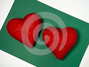 Two red hearts on a green background. Postcard for valentine\'s day. Romantic background