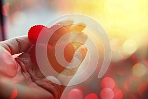 Two red hearts in a hand on a palm. Light background, sunny flare. The concept of love. Valentine`s Day