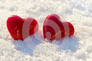 Two red hearts on ice wet snow, selective focus