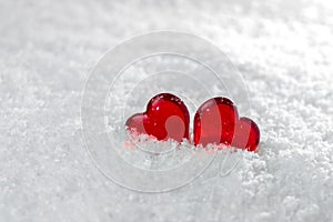 Two red hearts lie on the white fluffy snow in winter. Symbol of love. Valentine`s day