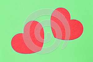Two red hearts on a light green background closeup. Greeting card with copy space. Valentine`s Day concept