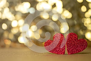 Two red hearts like a couple on a gold glitter and sequin background