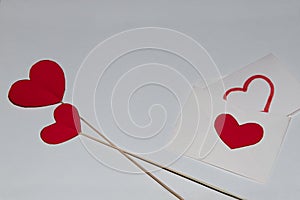 Two red hearts made of cardboard, a white envelope and a message with a painted heart.