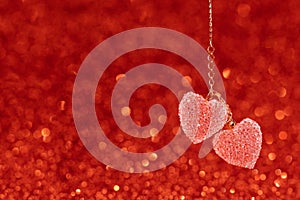 Two Red hearts pendant, valentine day greeting card. Bokeh background.
