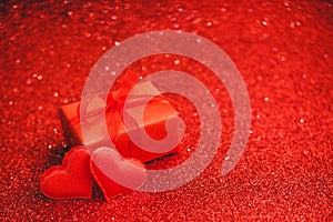 Two red hearts and red gift box on a red background of sparkles. Valentines day, love, romance, dating, gift present, anniversary