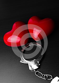 Two red hearts and steel handcuffs on dark background.St Valentine day and Fifty shade of black concept