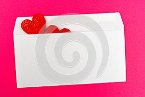 Two red hearts in a white envelope