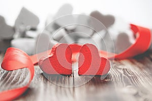 Two red hearts on wooden background with red ribbon