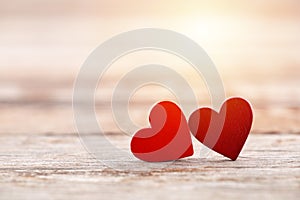 Two red hearts on wooden background in sunset