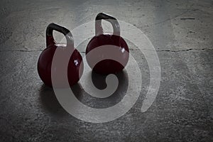 Two red kettlebells on a stone floor in a gym - background light photo