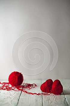 Two red knitted hearts and a ball of yarn