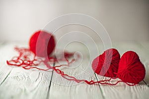 Two red knitted hearts and a ball of yarn