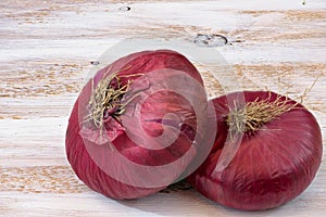 Two red onions on the white painted wooden background.