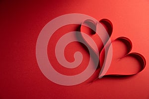 Two red paper hearts on red paper background. Love and Valentine`s day concept