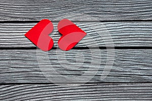 Two red paper hearts in shape of kissing lips on textured gray wood