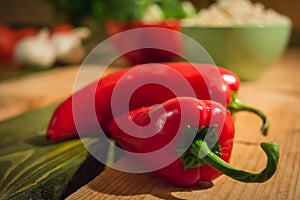 Two red peppers lying on a wooden table