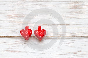 Two red polka-dot hearts on clothespins over wood border. Valentines day background