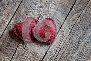 Two red soft woolen hearts on a wooden table background
