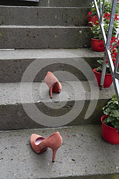 Two red stiletto high heals staning outside on steps of stairs after an party