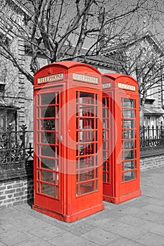 Two Red Telephone Booth on black and white backgrounding the city of London, UK