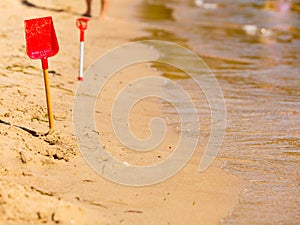 Two red toy shovels in sand on beach